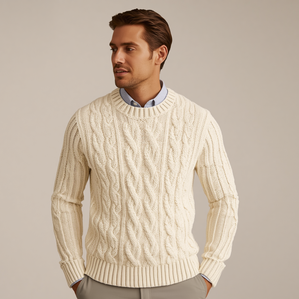 Mann trägt einen beigen Pullover mit Zopfmuster, Rundhalsausschnitt und langen Ärmeln über einem Hemd vor hellem Hintergrund.